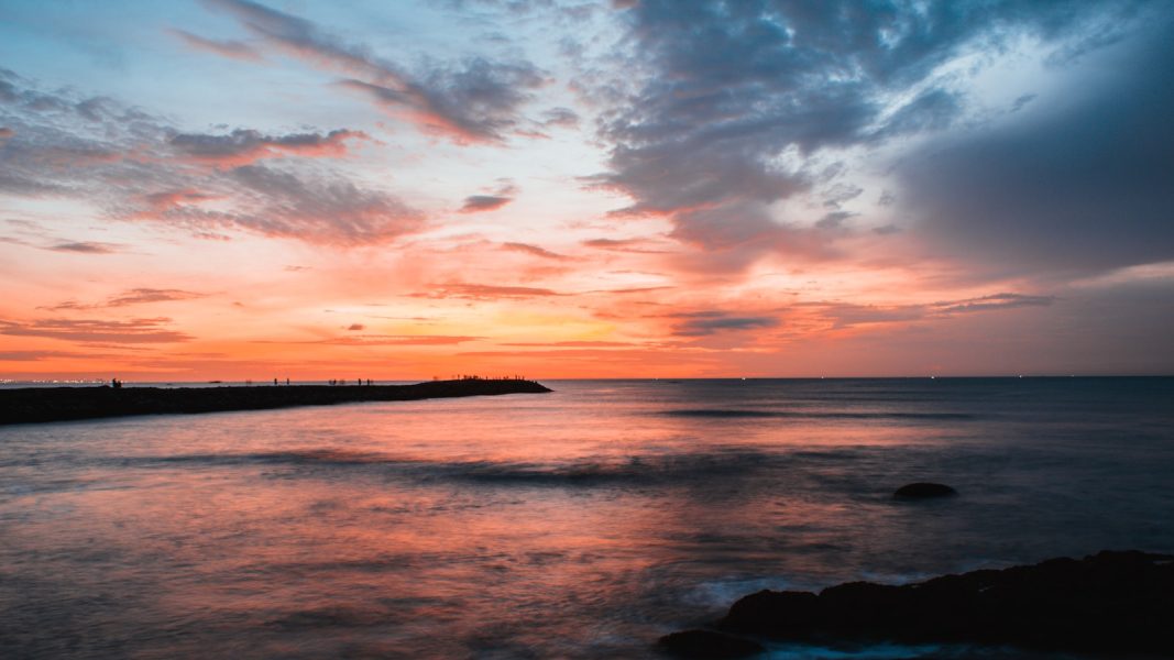 A sunset over a body of water with clouds in the sky