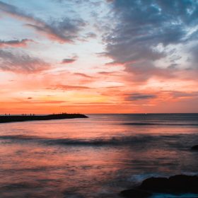A sunset over a body of water with clouds in the sky